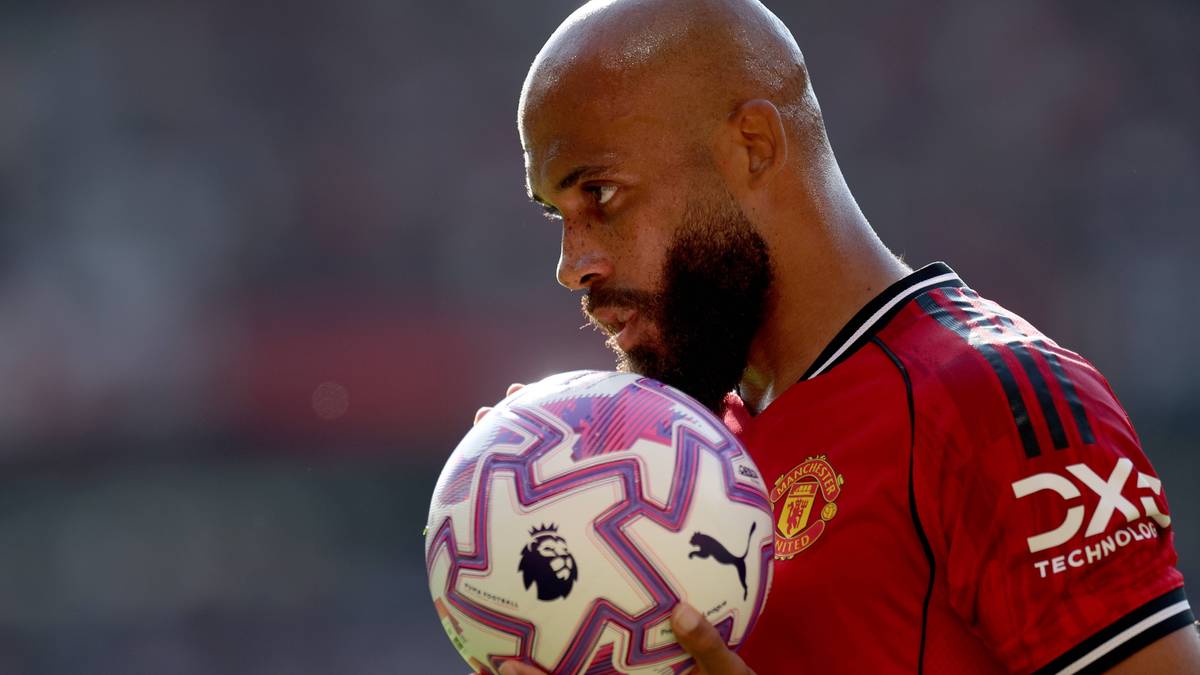 Piłkarz Manchesteru United z łysą głową i brodą trzyma piłkę do piłki nożnej.