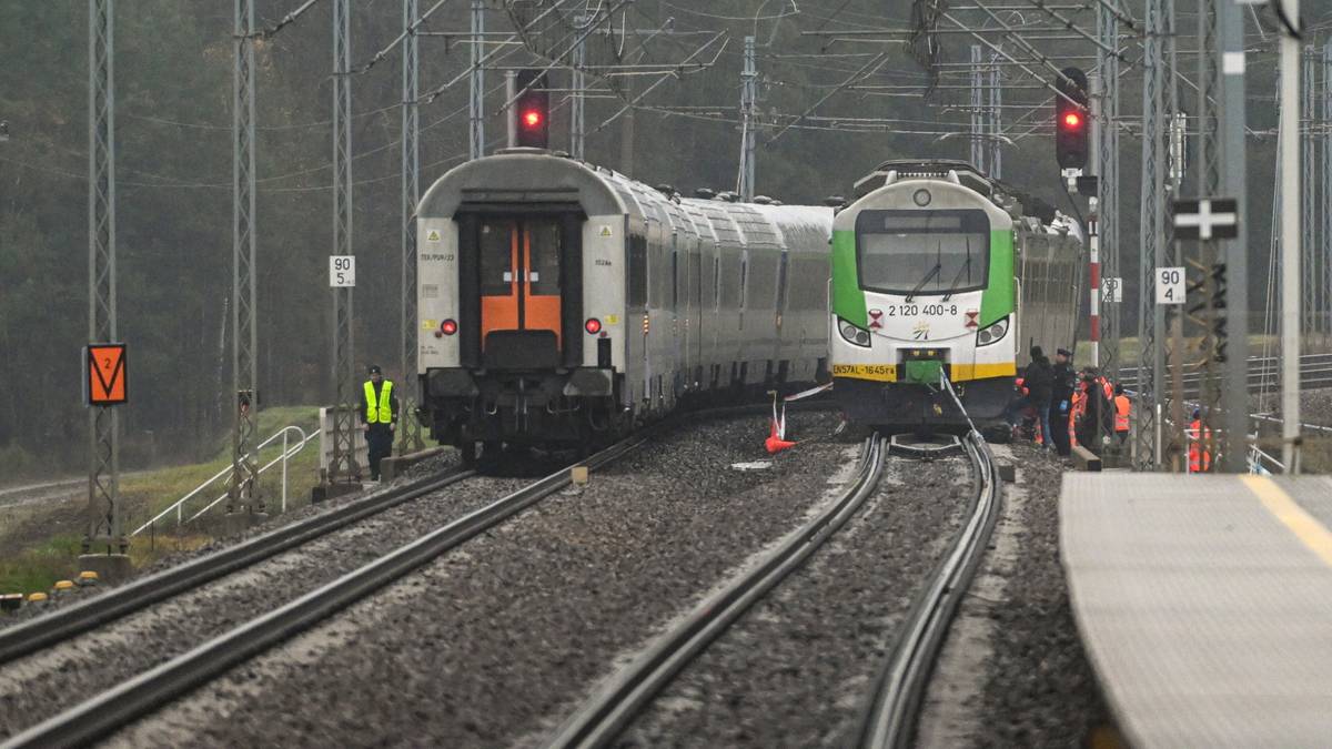 Dwa pociągi na torach kolejowych, z sygnalizacją świetlną w tle.