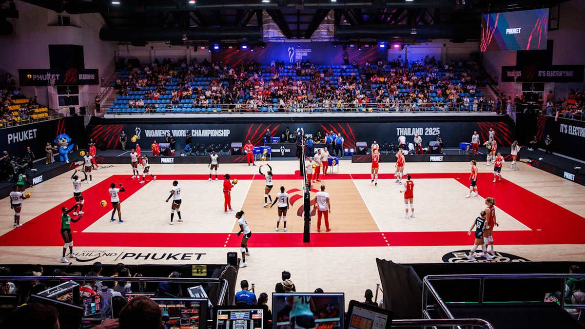 Drużyny siatkarskie rozgrywają mecz na hali sportowej, na trybunach siedzą widzowie.