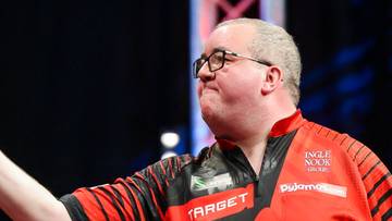 Mężczyzna w okularach rzuca lotką, ubrany w koszulkę z napisem TARGET.