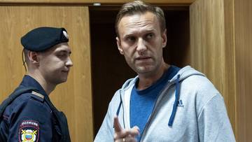 Aleksiej Nawalny wskazuje palcem, obok niego stoi funkcjonariusz w mundurze.