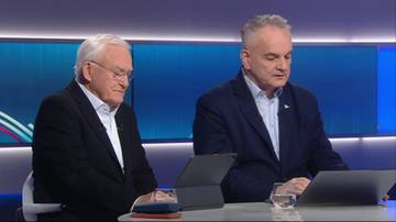 Dw&oacute;ch starszych mężczyzn siedzi przy stole, patrząc na laptopy. Na stole stoi szklanka z wodą. W tle widać niebieskie ekrany.