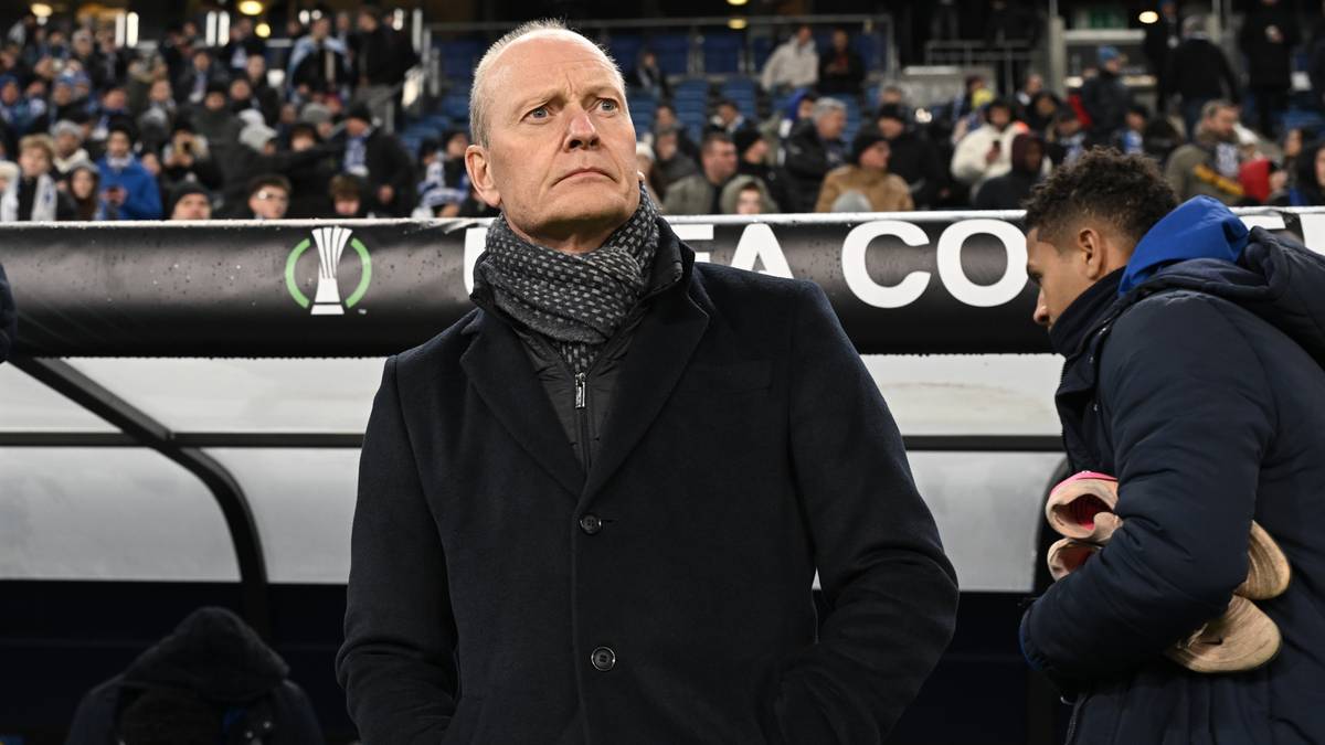 Trener FC Lausanne-Sport Peter Zeidler w czarnym płaszczu i szaliku stoi na tle trybun pełnych kibiców.