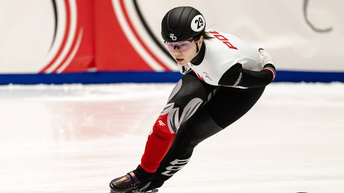 Zawodniczka short tracku w pozycji wyścigowej na lodowisku.