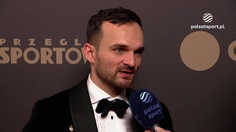 Portret Bartosza Zmarzlika, polskiego żużlowca, który jest w trakcie udzielania wywiadu. Ma na sobie czarny smoking z muszką i trzyma mikrofon.