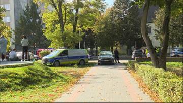 Widok na ulicę w mieście, przy kt&oacute;rej stoją radiowozy policyjne oraz funkcjonariusze.
