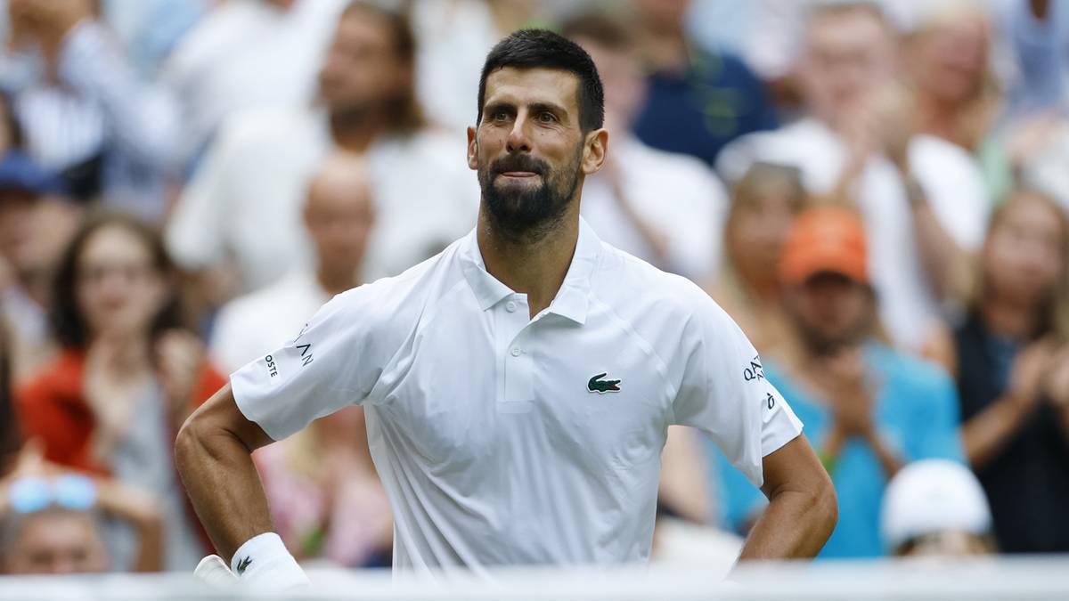 Novak Djoković w białej koszulce z kołnierzykiem i logo Lacoste, z dumą patrzy przed siebie, podczas meczu na US Open.