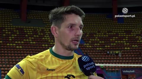 Portret siatkarza Miłosza Zniszczoła w ż&oacute;łtej koszulce z zielonymi akcentami. Jest podczas wywiadu, a w tle widać trybuny wypełnione widzami.