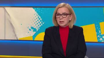 Kobieta w okularach i czarnym garniturze, ubrana w czerwony golf, wypowiada się na tle kolorowej scenografii studyjnej.