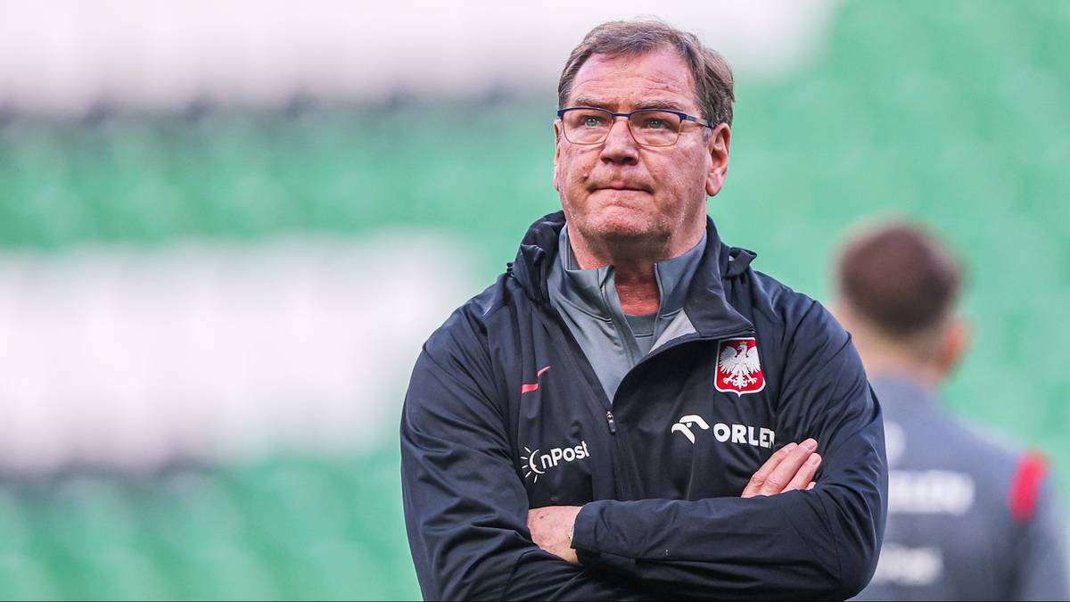 Jan Urban, trener reprezentacji Polski w piłce nożnej, stoi ze skrzyżowanymi rękami i patrzy w dal.