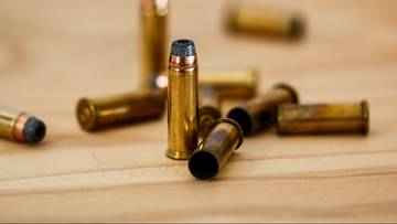 Zbliżenie na kilka nabojów kalibru .45 ACP leżących na drewnianej powierzchni.