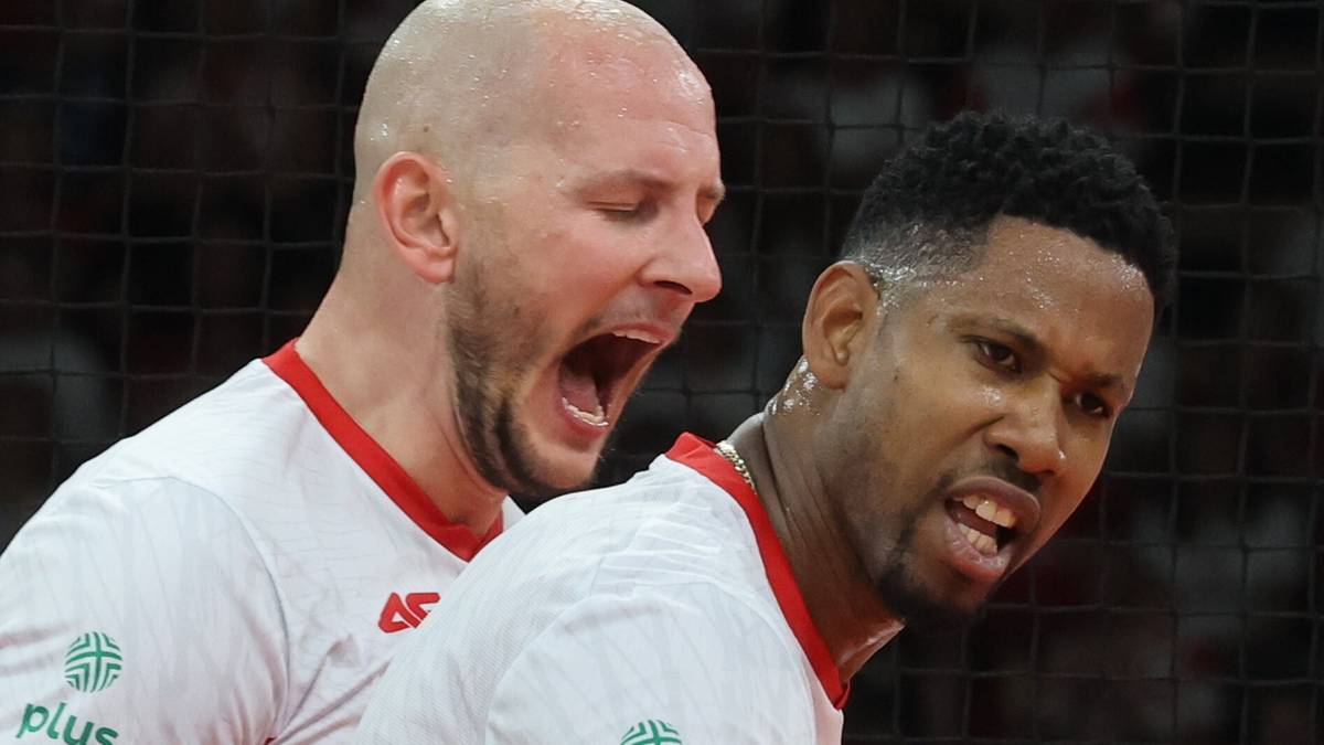 Dwóch siatkarzy w białych koszulkach, jeden krzyczy z otwartymi ustami, drugi patrzy z determinacją.