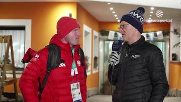 Maciej Maciusiak w czerwonej kurtce i czapce rozmawia z dziennikarzem w czarnej kurtce i granatowej czapce, trzymającym mikrofon.