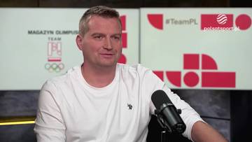 Mężczyzna w białej koszulce siedzi przed mikrofonem w studiu telewizyjnym.