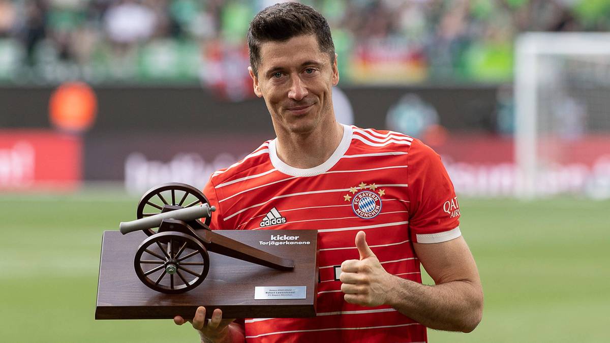 Piłkarz Robert Lewandowski trzyma w ręku statuetkę w kształcie armaty.