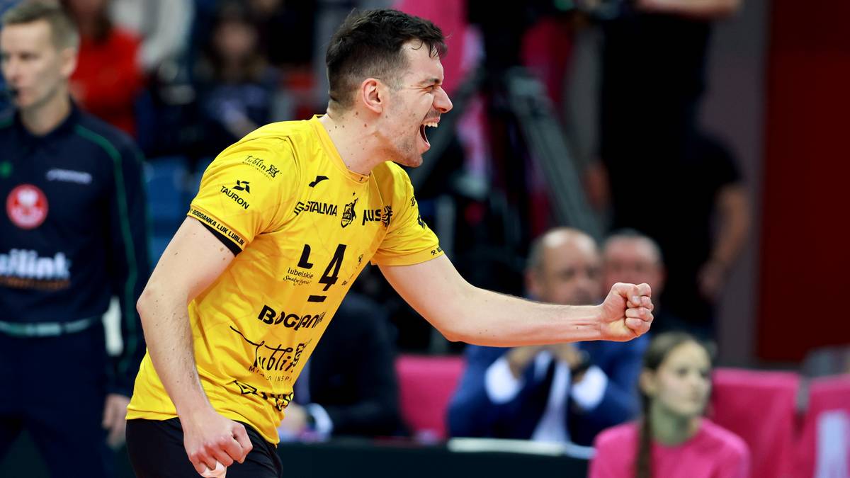 Siatkarz w ż&oacute;łtej koszulce z numerem 14 krzyczy z radości, zaciskając pięść.