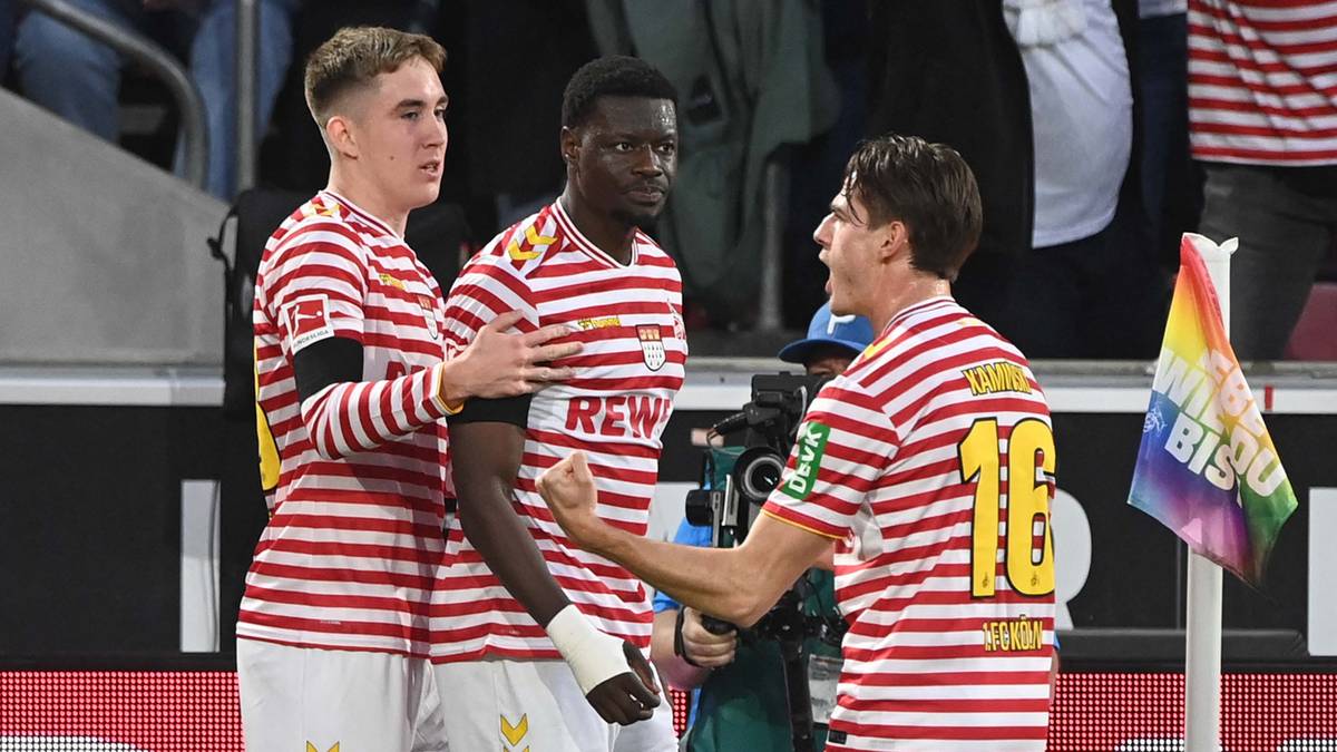 Piłkarze w pasiaste koszulki świętują zdobycie bramki, jeden z nich jest przy baloniku z tęczowymi barwami.