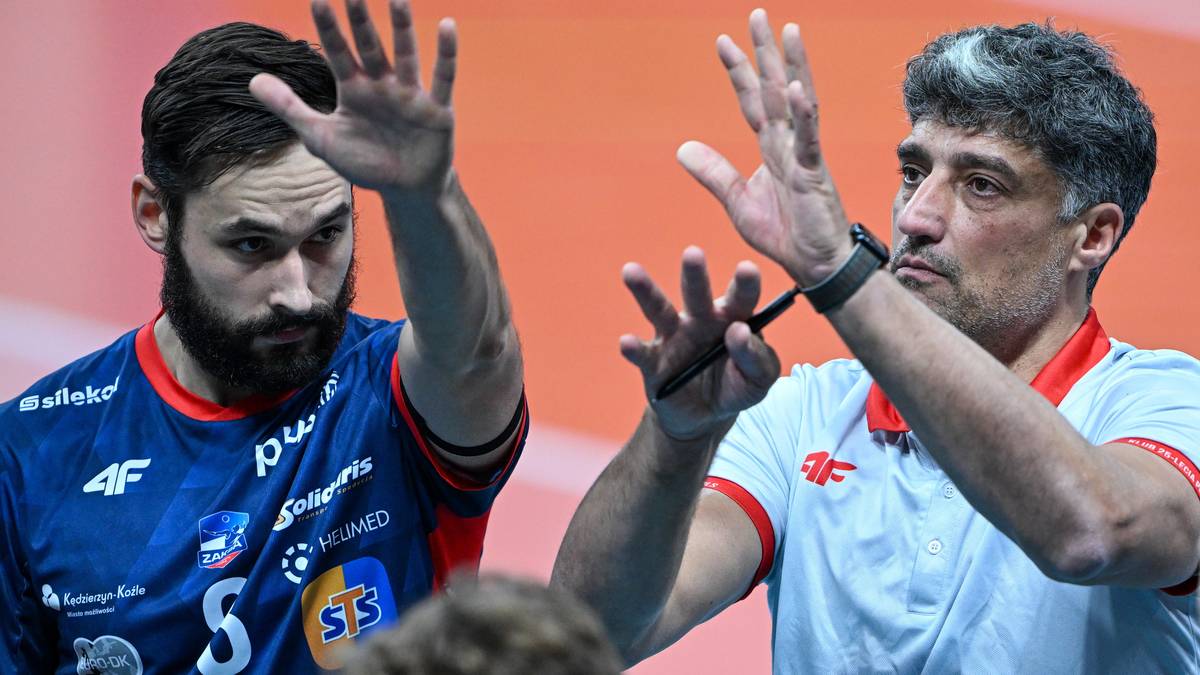 Siatkarz w niebieskiej koszulce i trener w białej koszulce na boisku.