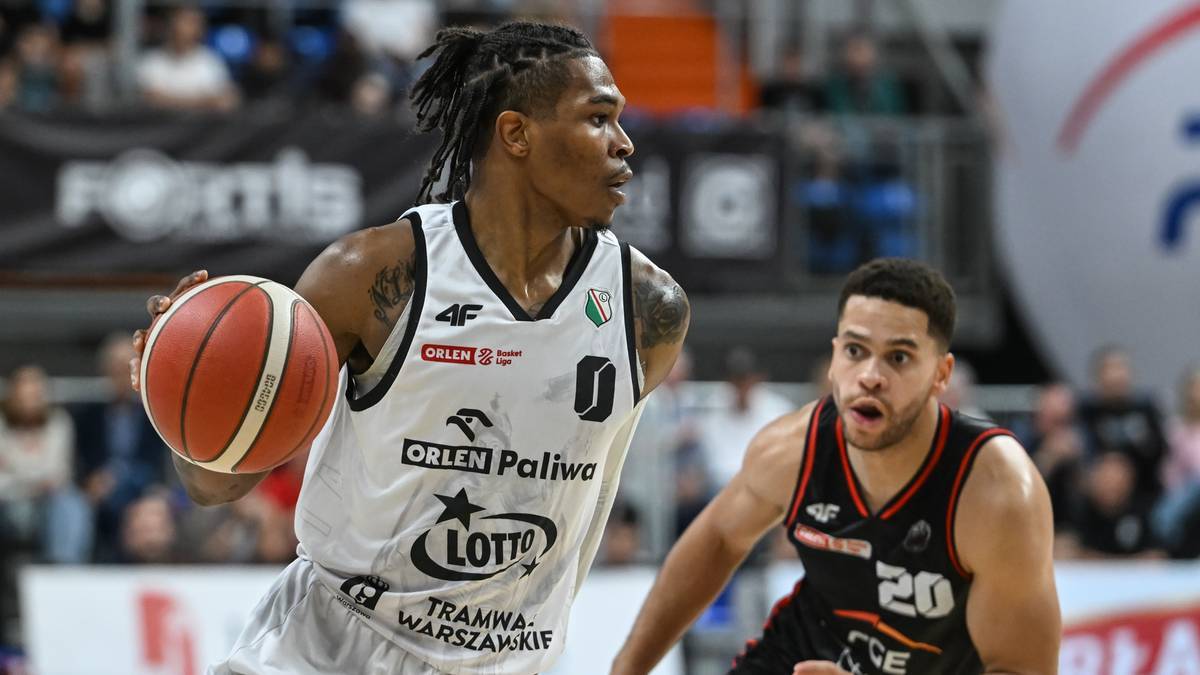 Zbliżenie na rękę koszykarza trzymającego pomarańczową piłkę do koszykówki z białymi pasami.