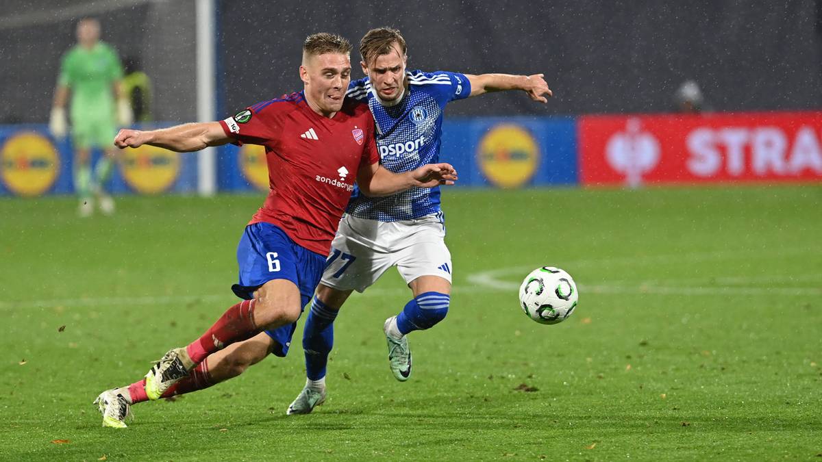 Dwóch piłkarzy walczy o piłkę na boisku podczas meczu.