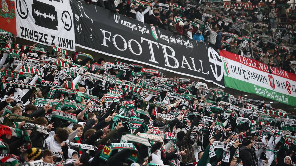 Tłum kibiców na stadionie z transparentami i szalikami.