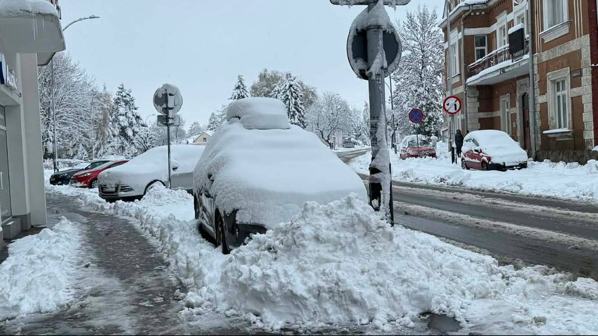 Zaśnieżona ulica z samochodami i budynkami w zimowej scenerii