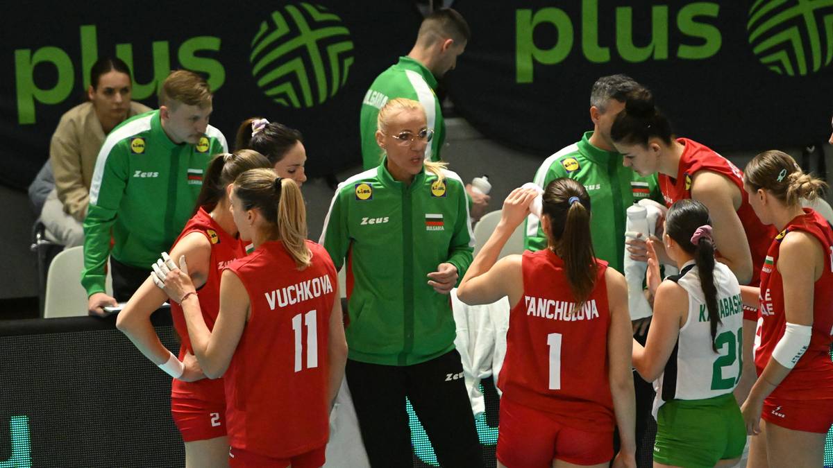 Grupa siatkarek i trenera stojących na boisku, większość w strojach sportowych.