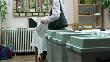 Kobieta wrzuca kartę do głosowania do urny wyborczej.