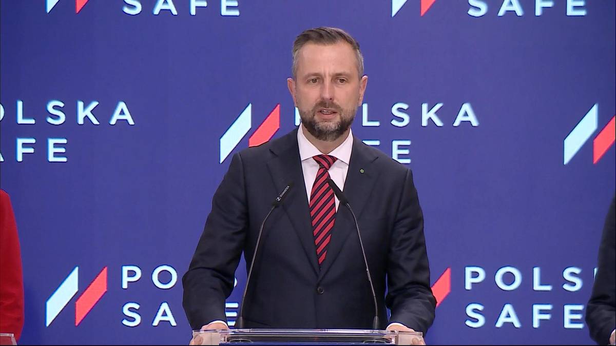 Mężczyzna w garniturze przemawia za m&oacute;wnicą.