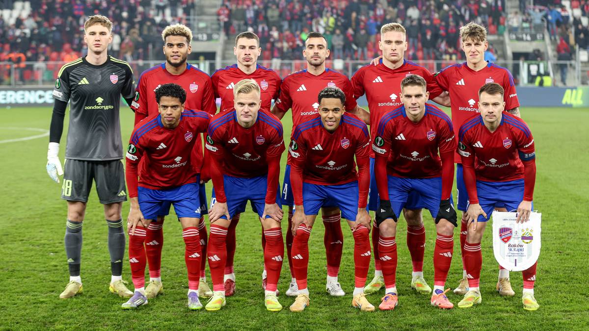 Drużyna piłkarska w czerwono-niebieskich strojach na boisku.