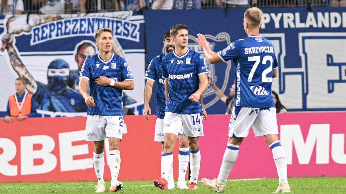 Trzech piłkarzy Lecha Poznań w niebieskich strojach radośnie świętuje zdobycie bramki.