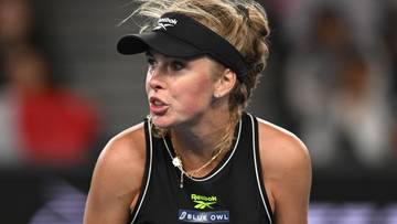 Portret tenisistki Magdaleny Fręch podczas meczu, noszącej czarną czapkę z daszkiem i czarny top sportowy.