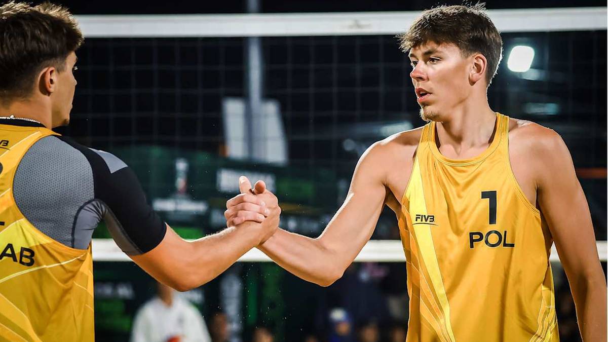 Dwóch siatkarzy plażowych w żółtych koszulkach ściska sobie dłonie po meczu. Jeden z nich ma numer 1 i napis "POL" na koszulce.