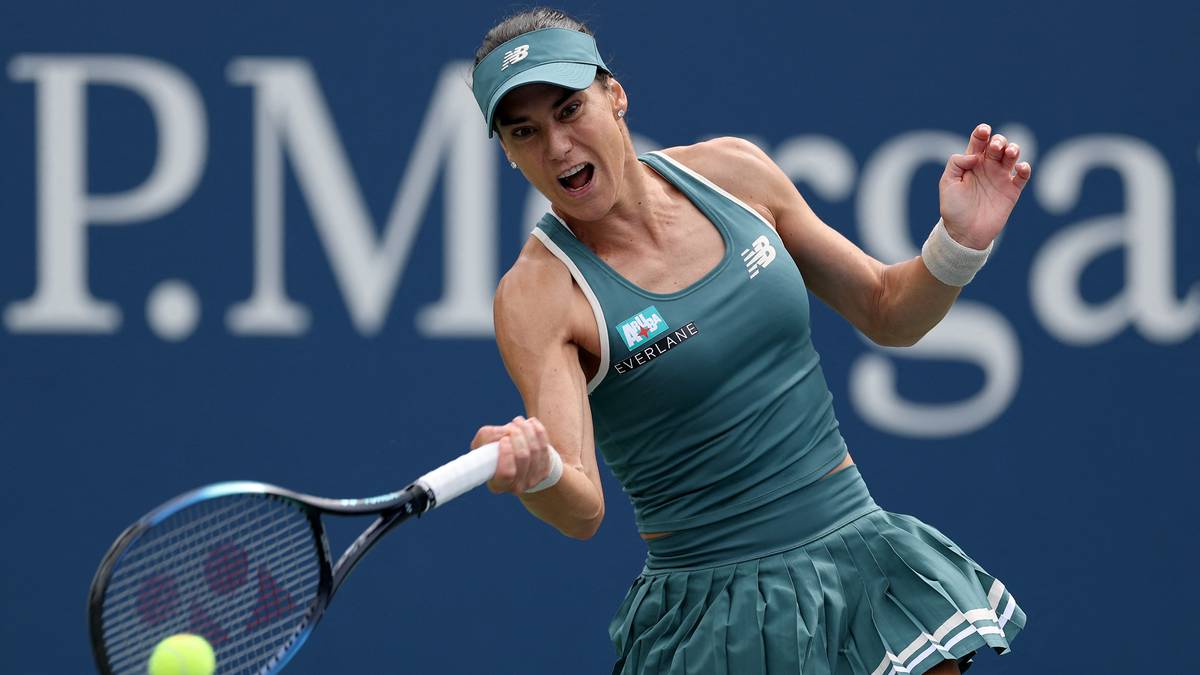 Iga Świątek w akcji podczas meczu tenisowego, uderza piłkę rakietą.