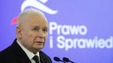 Jarosław Kaczyński w garniturze i białej koszuli z krawatem, na tle niebieskiego baneru z napisem "Prawo i Sprawiedliwość" i stylizowanym orłem.
