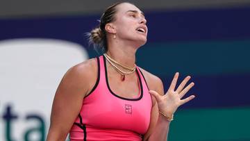 Tenisistka Aryna Sabalenka w różowej sukience sportowej trzyma rakietę tenisową.
