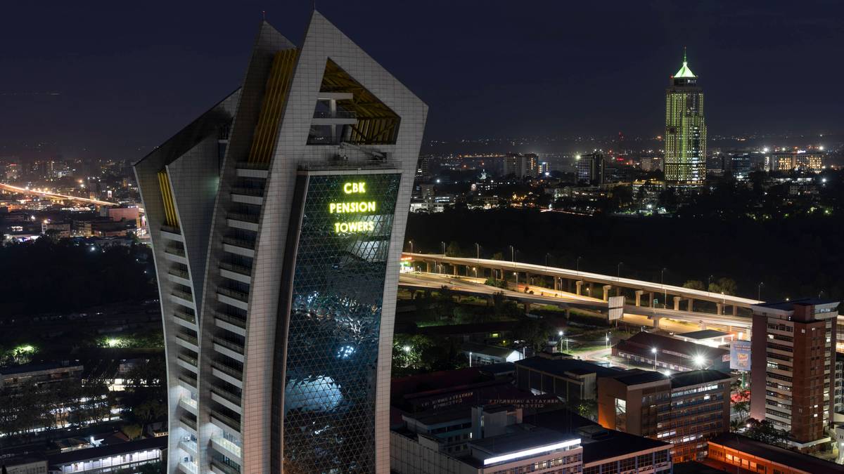 Wieżowiec "CIE Pension Towers" o nowoczesnej architekturze, oświetlony nocą, na tle panoramy miasta z innymi budynkami i autostradą z widocznymi światłami.