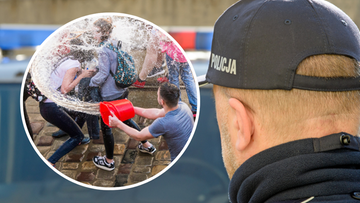 Zbliżenie na czapkę policjanta z napisem POLICJA na tle niewyraźnego tłumu os&oacute;b, na okrągłej wstawce widoczni są ludzie oblewający się wodą z wiadra.