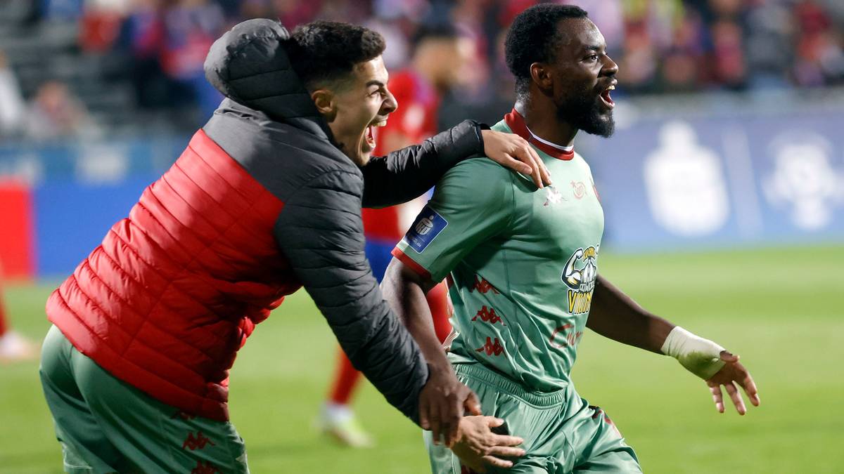 Dwóch piłkarzy biegnie po boisku, jeden obejmuje drugiego ramieniem.