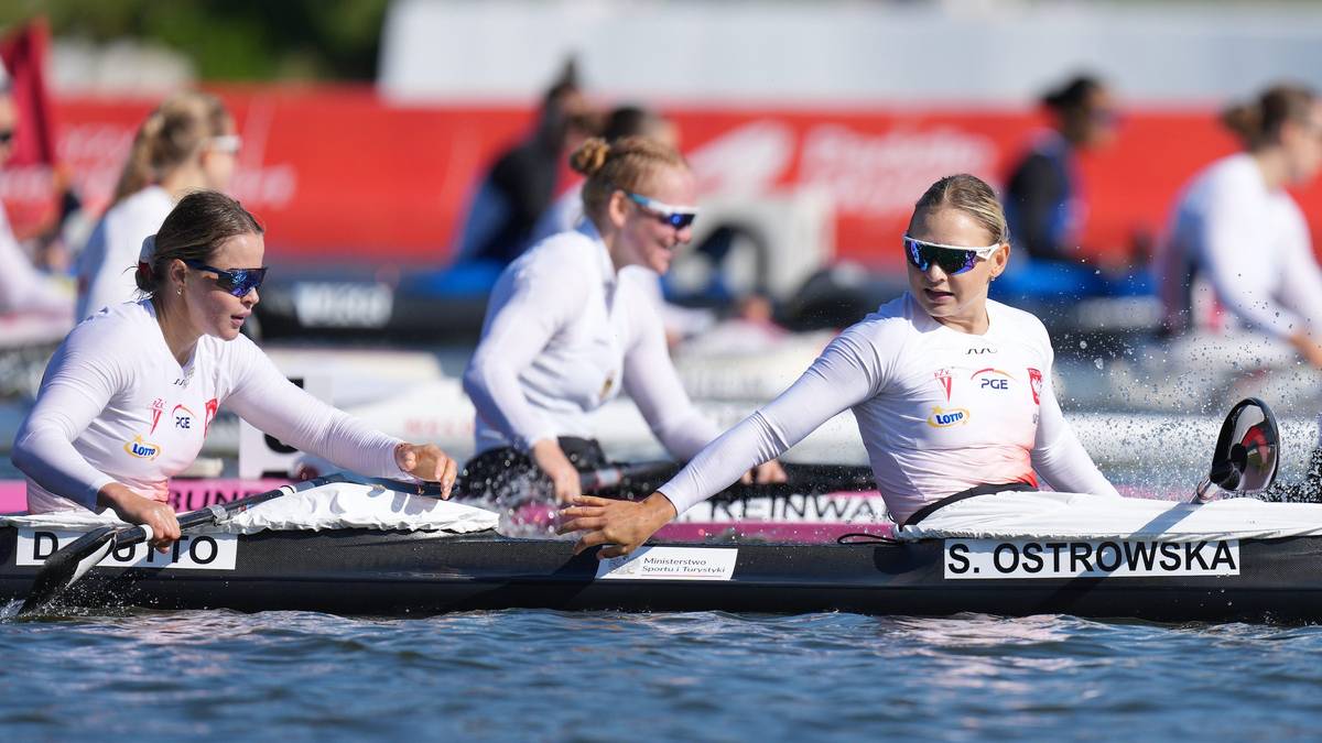 Polskie kajakarki w strojach sportowych siedzące w łodzi na torze regatowym.