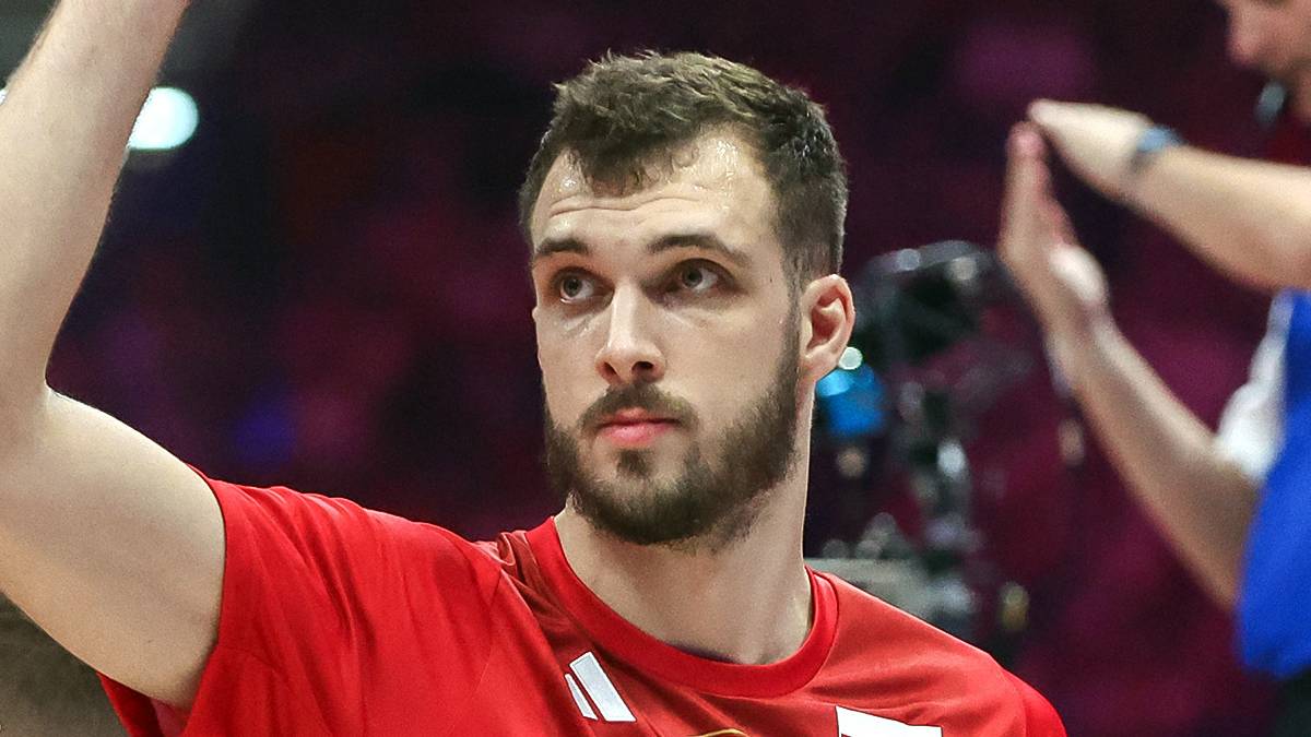 Siatkarz w czerwonej koszulce z numerem 99 podnosi rękę w geście triumfu.