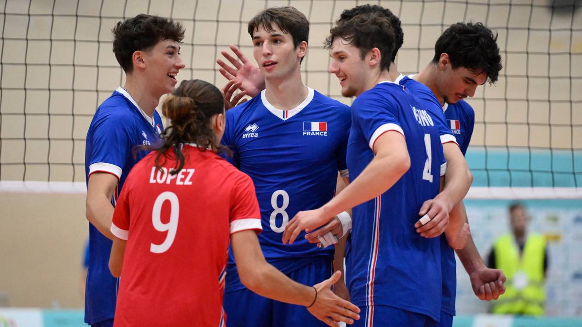 Grupa młodych mężczyzn w niebieskich strojach z francuskimi napisami na plecach, świętujących razem na boisku do siatkówki. Jeden z nich, w czerwonej koszulce z numerem 9, jest zwrócony plecami do widza.