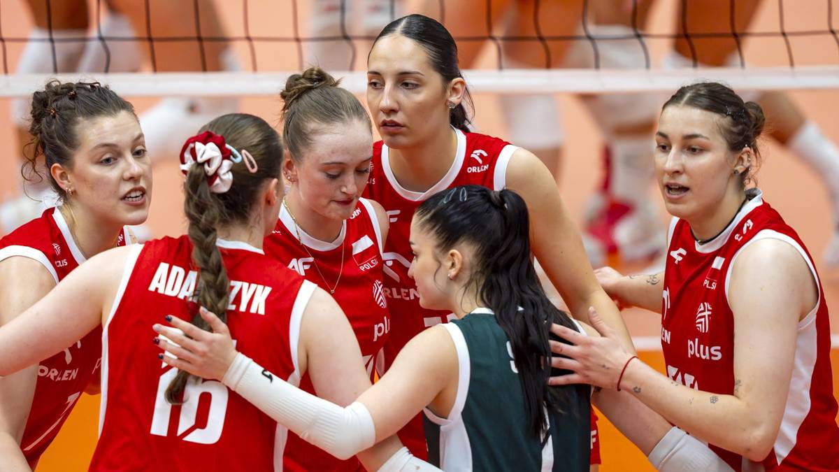 Grupa zawodniczek siatk&oacute;wki w czerwonych strojach sportowych otacza koleżankę z drużyny podczas meczu.