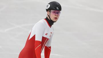 Polski panczenista w czerwono-białym stroju i kasku na lodowisku.