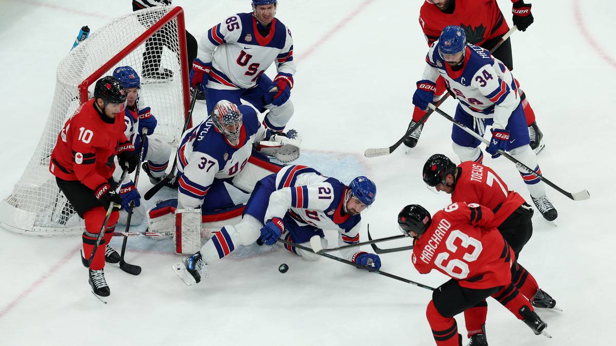 Hokeiści w akcji podczas meczu, walczący o krążek w okolicach bramki.