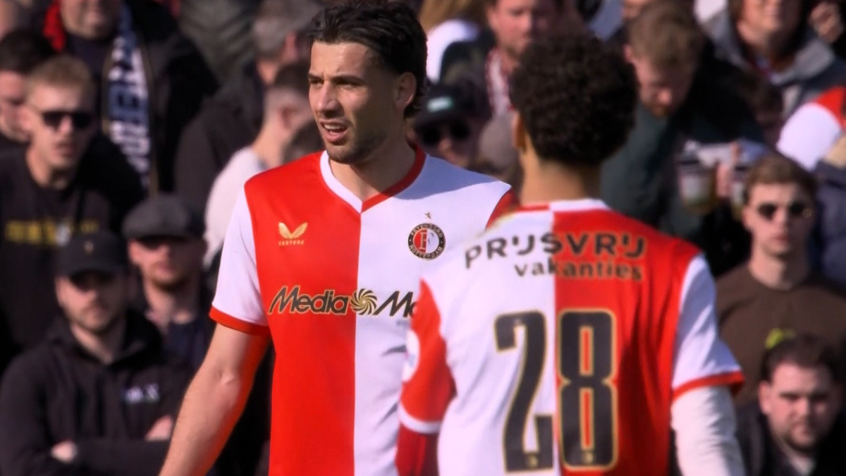 Dw&oacute;ch piłkarzy w strojach Feyenoordu podczas meczu, jeden z nich jest zwr&oacute;cony przodem do kamery, a drugi tyłem z widocznym numerem 28.