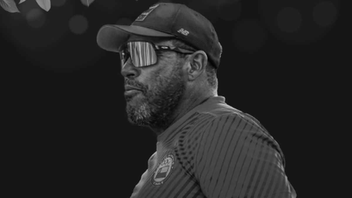 Portret czarno-biały siatkarza w okularach przeciwsłonecznych i czapce z daszkiem, patrzący w bok.