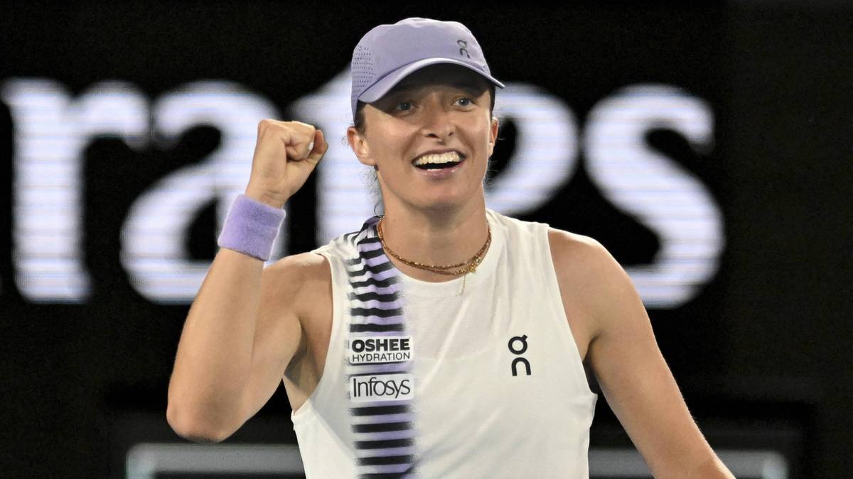 Iga Świątek świętuje zwycięstwo, ma na sobie biały strój sportowy i czapkę z daszkiem.