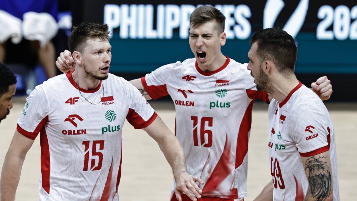 Trzech siatkarzy w białych koszulkach z czerwonymi detalami dyskutuje na boisku.