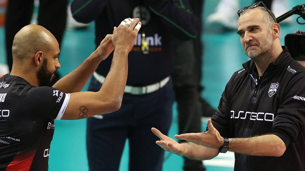 Dw&oacute;ch siatkarzy w strojach sportowych rozmawia na boisku.